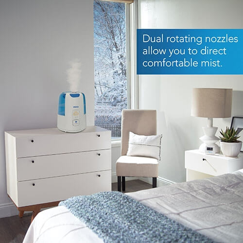 Vicks Dual Comfort Cool and Warm Mist Humidifier releasing mist in a medium sized room with text dual rotating nozzles allow you to direct comfortable mist.