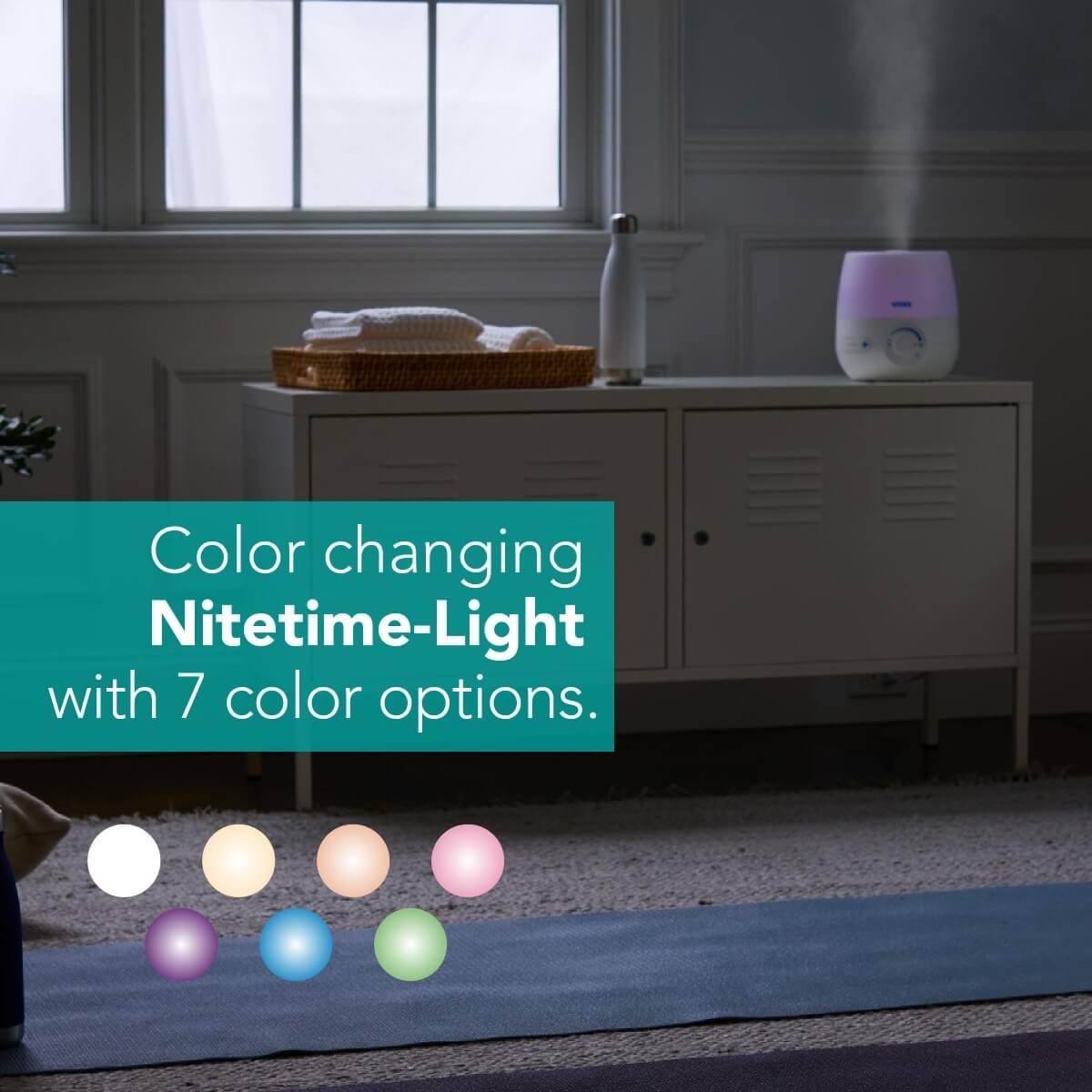 Vicks NaturalCare™ Cool Mist Ultrasonic Humidifier in a small room releasing cool mist with color light on