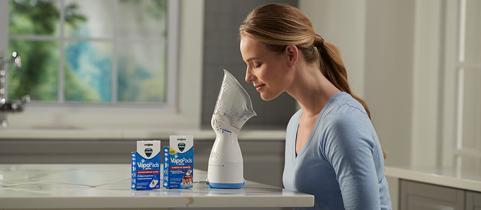 Humidifiers for Allergies: Woman inhaling steam from a Vicks Sinus Inhaler